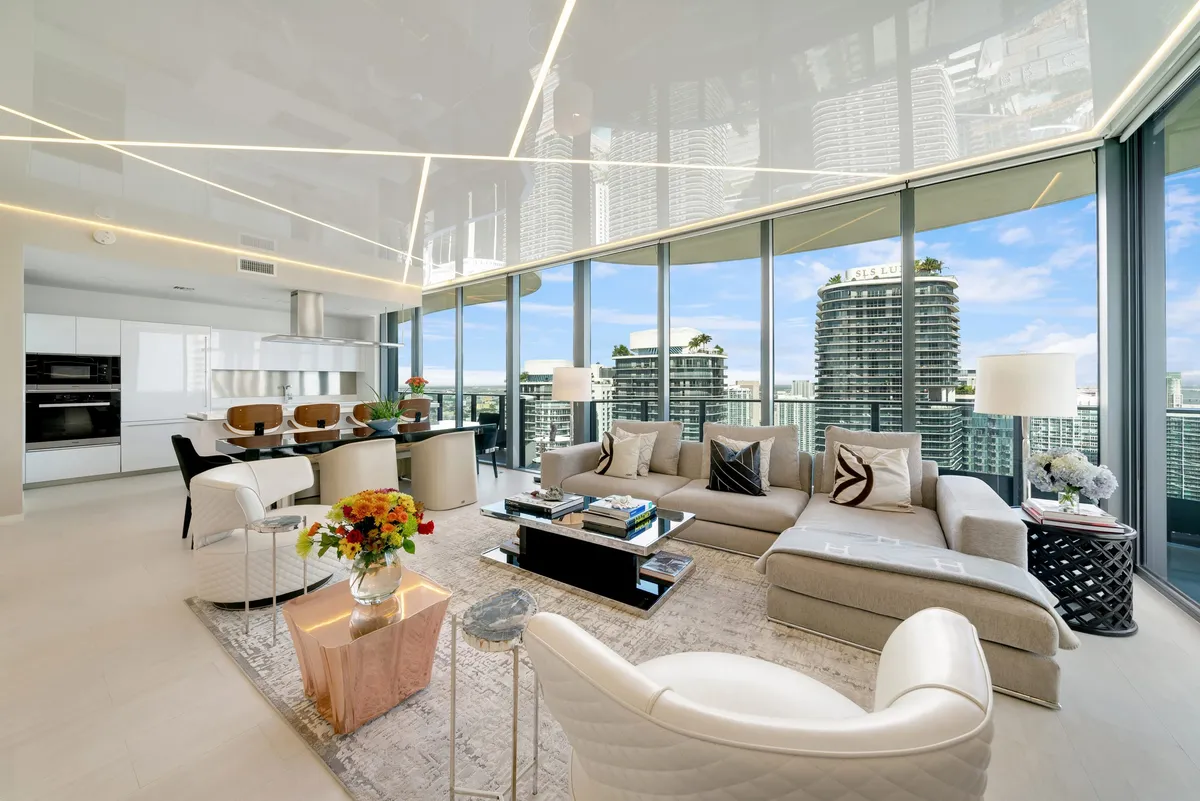 Penthouse living room with curved sectional sofas, gold coffee tables, and panoramic city skyline