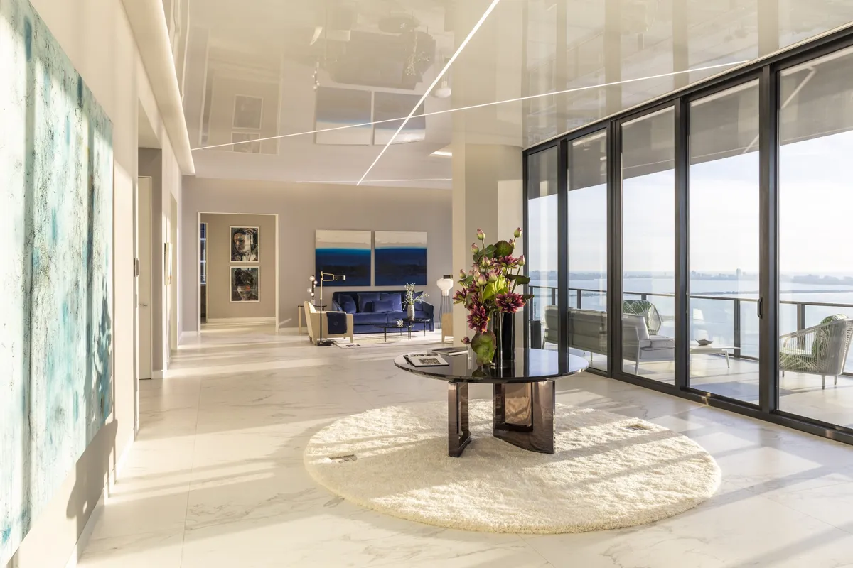 Grand waterfront condo foyer with round entry table, art on walls, and ocean balcony view