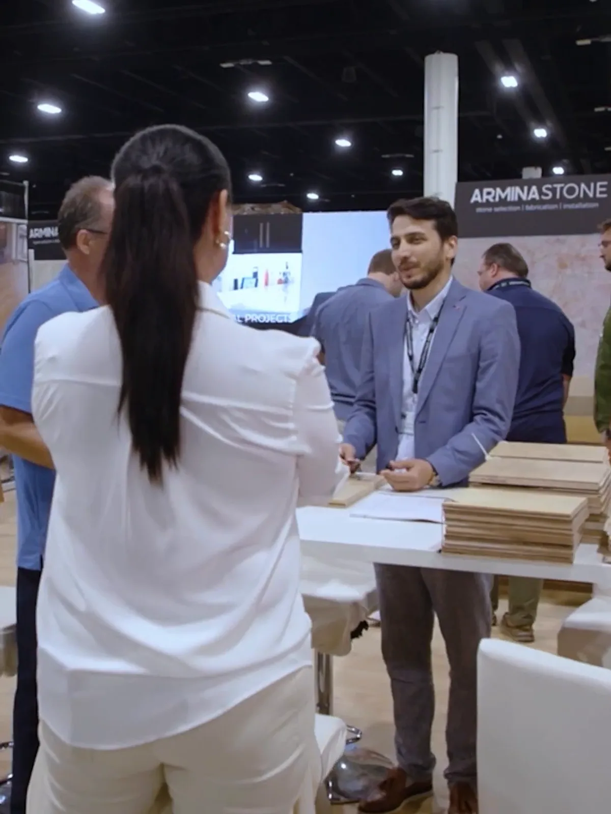 Exhibitor rep presenting stone samples to an attendee at the Armina Stone booth, Miami Home Show